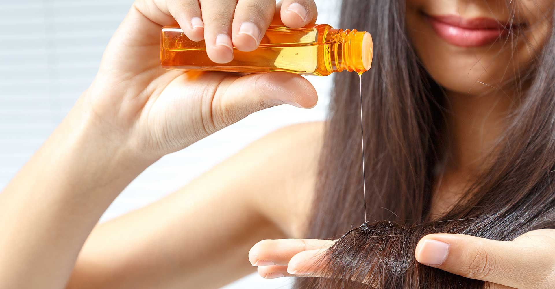 Modelo com cabelo liso passando produto em seu cabelo